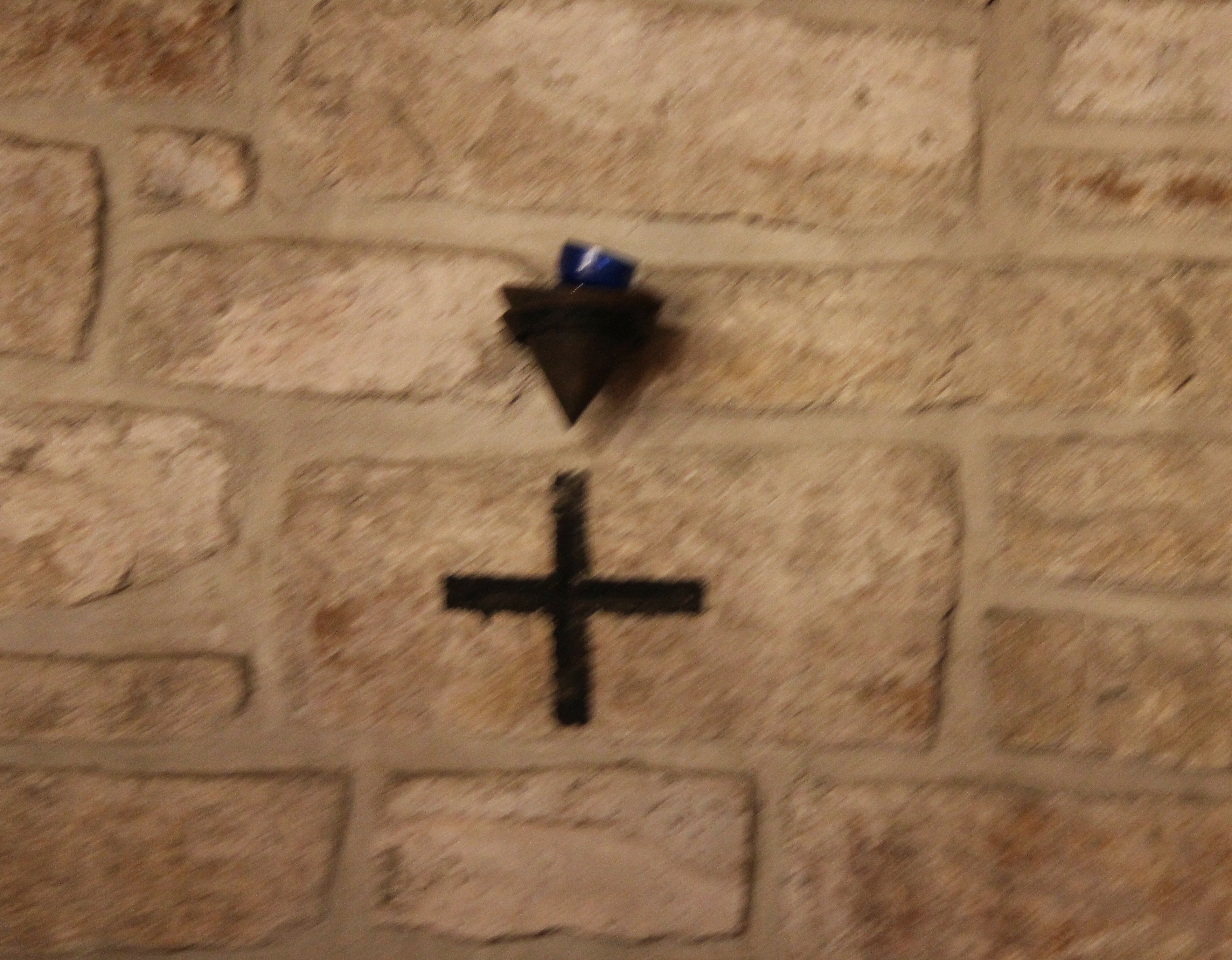 Croix gravée dans la pierre avec, à proximité, un petit récipient de forme conique (destiné à recevoir une lumière, une décoration... ?